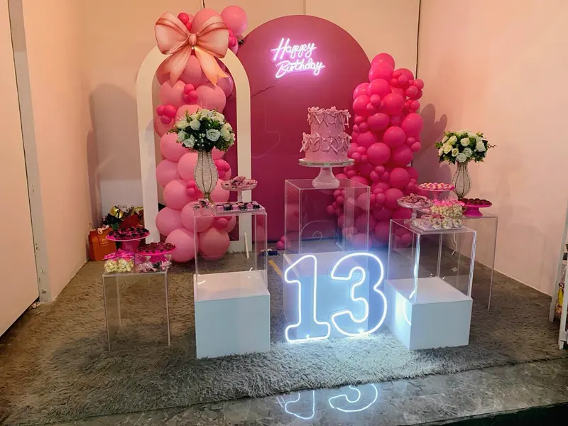 Mesa de aniversário de 13 anos em tons de rosa, com balões e letreiro neon