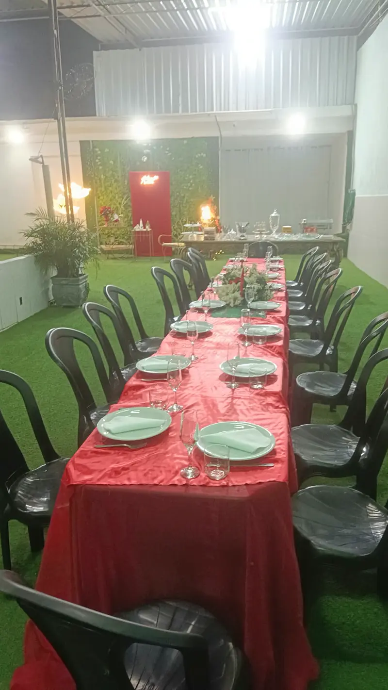 Mesa comprida posta para jantar com toalhas vermelhas no gramado