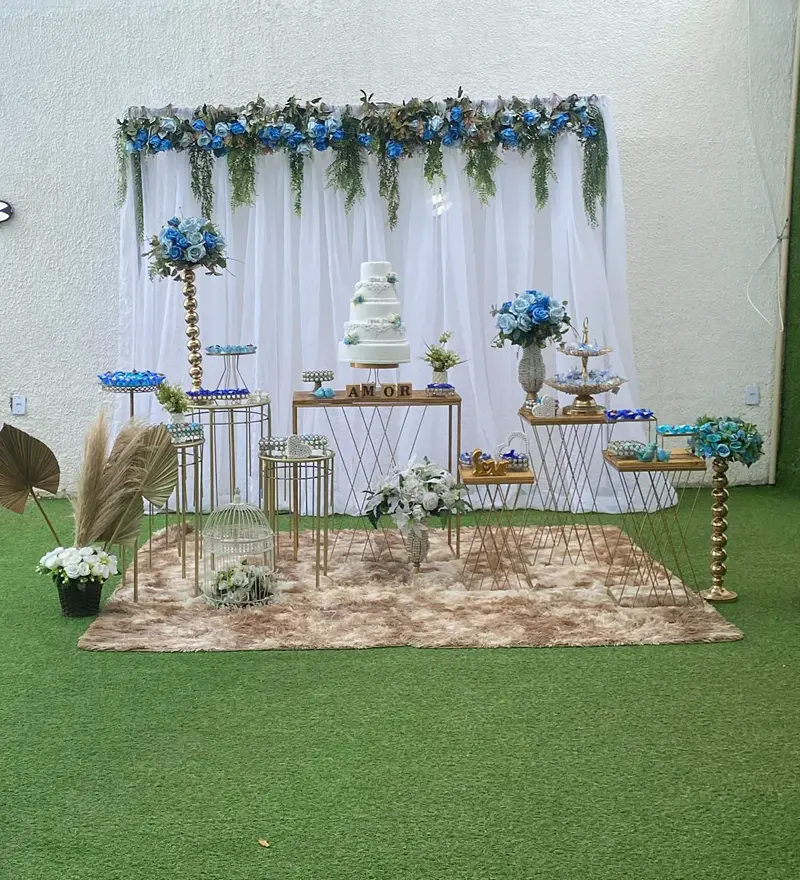 Mesa de bolo branca com flores azuis montada no gramado